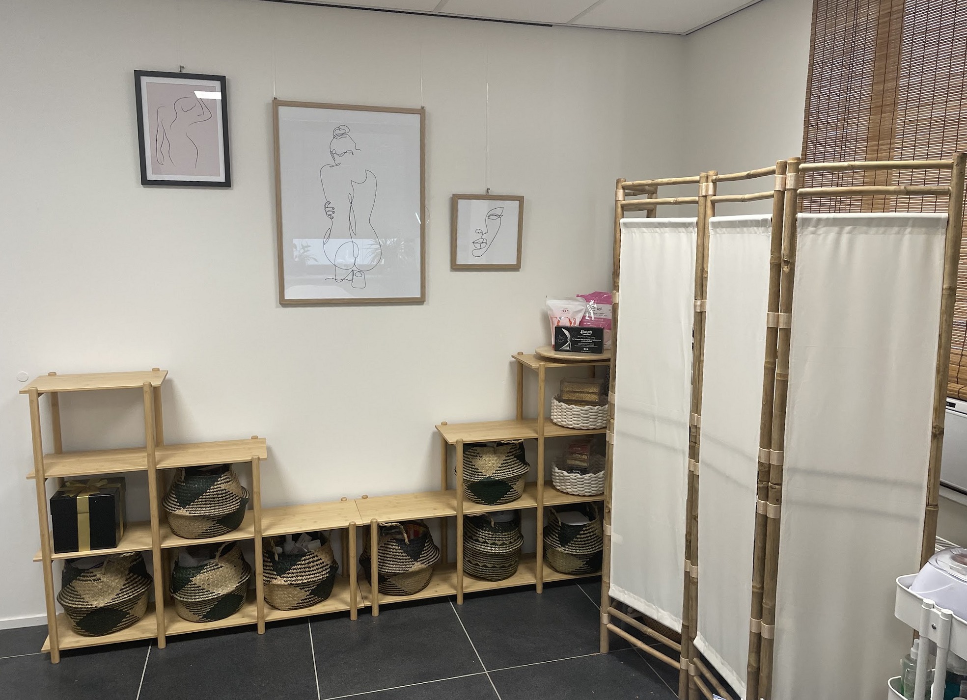 Wandprints, een houten vakkenkast met mandjes en een vouwscherm van bamboe en linnen